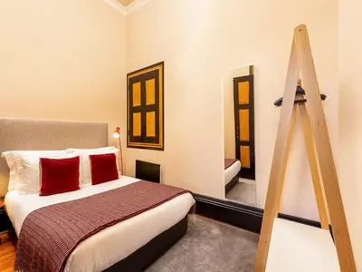 a bedroom with a bed with red pillows and a ladder at Cosy apartment in heart of Porto in Porto