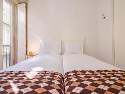 a bedroom with two beds with a checkered blanket at Central Porto apartment with balcony in Porto
