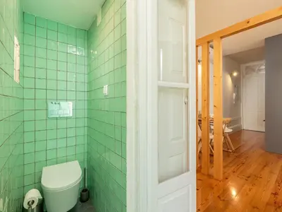 a bathroom with green tiled walls and a toilet at Modern Porto studio with essential amenities in Porto