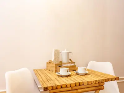 a wooden table with white chairs and cups on it at Modern Porto studio with essential amenities in Porto