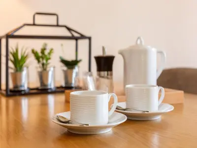 three white cups and saucers on a wooden table at Beach studio nearby market in Oporto in Porto