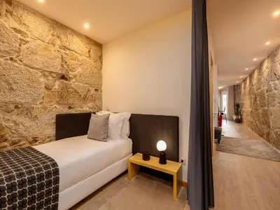 a bedroom with a bed and a stone wall at Apartment in Vila Nova de Gaia in Vila Nova de Gaia