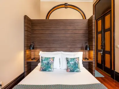a bedroom with a bed with a wooden headboard and two pillows at Well-maintained air conditioned studio in Porto in Porto