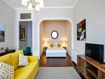 a living room with a yellow couch and a tv at Spacious city apartment with modern amenities in Porto