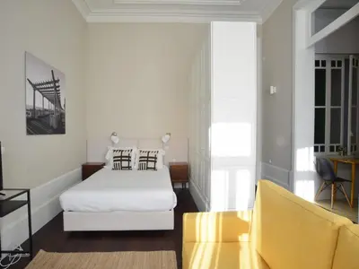 a bedroom with a white bed and a yellow couch at Beautiful apartment in Oporto in Porto