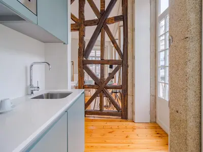 a barn door in a kitchen with white cabinets and a wooden floor at Charming studio in the heart of Porto in Porto