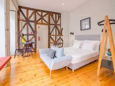 a bedroom with a white bed and a chair at Charming studio in the heart of Porto in Porto