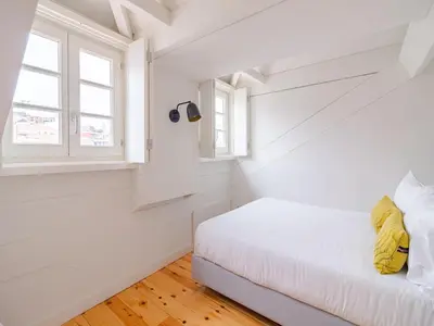 a white bedroom with a bed and a window at Comfortable apartment in Oporto in Porto