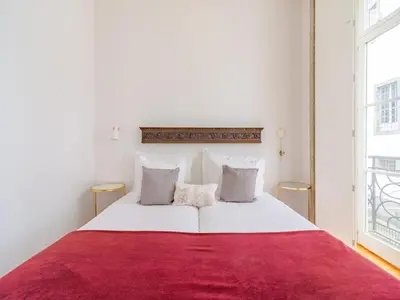 a bedroom with a large white bed with a red blanket at Quaint studio in the heart of Porto in Porto