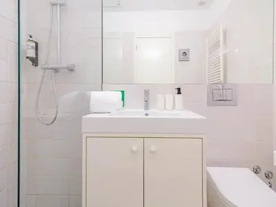a white bathroom with a sink and a shower at Quaint studio in the heart of Porto in Porto