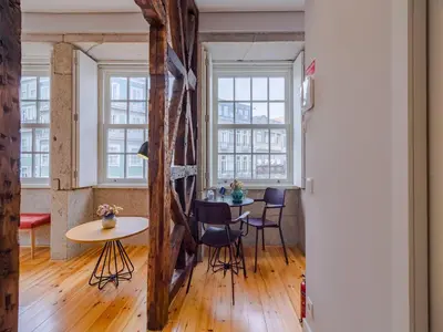 a room with a table and chairs and windows at City-center apartment with modern comforts in Porto