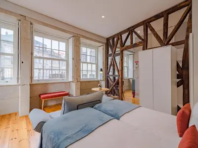 a bedroom with a large white bed and windows at City-center apartment with modern comforts in Porto