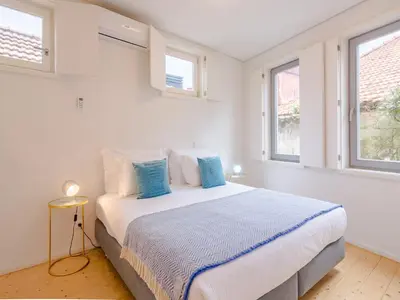 a white bedroom with a large bed with blue pillows at Charming studio, ideal for smaller groups in Porto