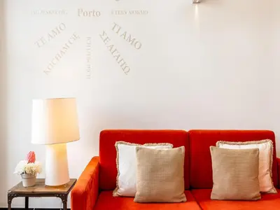 a red couch in a living room with a clock on the wall at Apartment near Praia da Luz beach in Porto