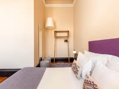 a bedroom with a bed with white sheets and a purple headboard at Charming Porto Studio Central & Cozy in Porto