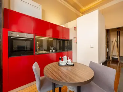 a kitchen with a wooden table and a red wall at Chic Porto Studio Cozy & Central Escape in Porto
