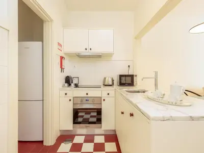 a white kitchen with a sink and a refrigerator at Cozy Getaway in Porto with Balcony in Porto