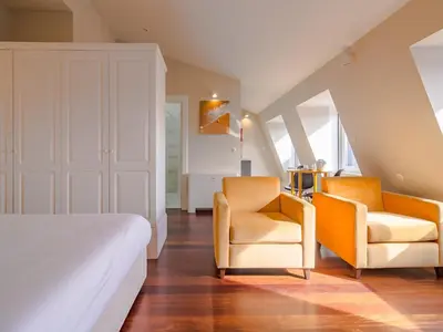 two orange chairs and a bed in a room at City-center apartment with modern comforts in Porto