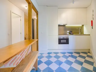 a kitchen with white cabinets and a blue and white floor at Central Porto Comfort Stay in Porto
