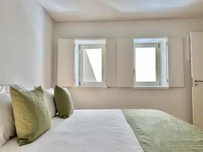 a white bed with two windows in a bedroom at Heart of Porto Cozy Escape in Porto