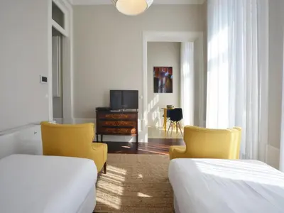 a bedroom with two beds and two chairs and a tv at Cozy and modern apartment in Porto in Porto