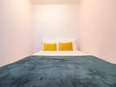 a white room with a bed with two yellow pillows at Charming studio, ideal for smaller groups in Porto