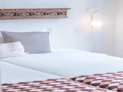 a white bed with a lamp on top of it at Charming studio, ideal for smaller groups in Porto