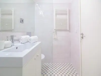 a white bathroom with a sink and a shower at Charming studio, ideal for smaller groups in Porto