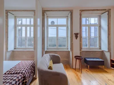 a living room with a couch and two windows at Charming studio, ideal for smaller groups in Porto