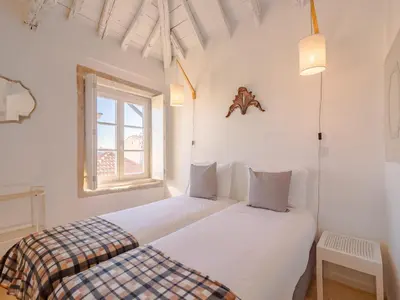 two beds in a room with white walls and a window at Cozy Porto studio perfect location & comfort in Porto