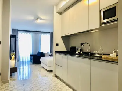 a kitchen with white cabinets and a living room at Bright and Spacious apartment in Porto in Porto