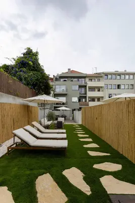 a garden with lounge chairs and an umbrella on the grass at Liiiving in Porto - Pool Paradise Apartments in Porto