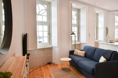 a living room with a blue couch and a tv at Central and comfortable apartment -downtown in Porto