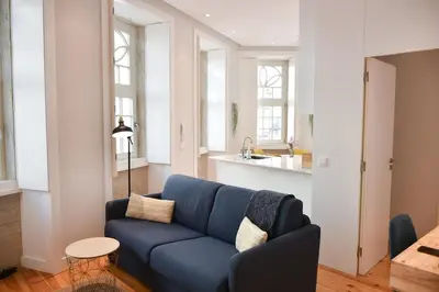 a living room with a blue couch and a kitchen at Central and comfortable apartment -downtown in Porto