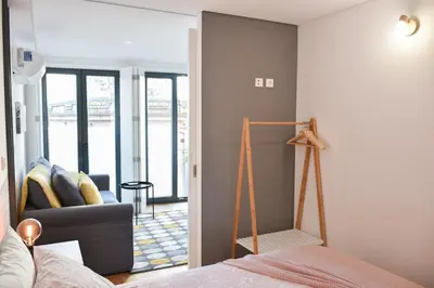 a bedroom with a bed and a living room at Central with balcony - 9 min-walk to Trindade in Porto