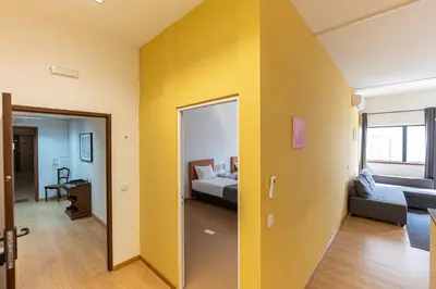 a yellow room with a bed and a couch at Oporto Spacious apartment in Porto