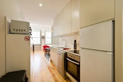 a kitchen with white cabinets and a white refrigerator at Aposentus - Premium Central Apartment 1BR in Porto