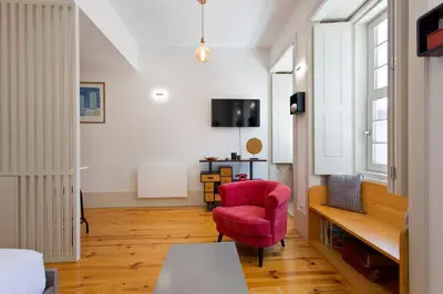 a living room with a red chair and a tv at Aposentus - Premium Central Apartment 1BR in Porto