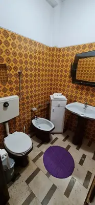 a bathroom with two toilets and two sinks and a purple rug at Catarina 711 in Porto