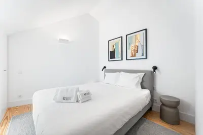 a white bedroom with a white bed and two pictures on the wall at GuestReady - D. Hugo Boutique Hotel B&B in Porto