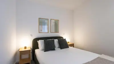 a bedroom with a white bed with two night stands at Bright 2BR Flat near Praça da Galiza by LovelyStay in Porto