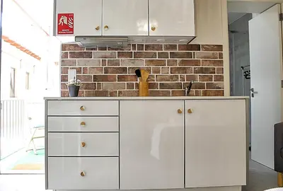 a kitchen with white cabinets and a brick wall at Art Quarter Oporto City Center in Porto
