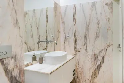 a bathroom with a white sink and a marble wall at Modern Studio in Porto Center, Ideal City Base in Porto