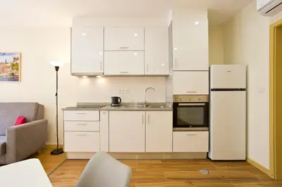a kitchen with white cabinets and a white refrigerator at Aposentus - CS Trindade Apartments in Porto
