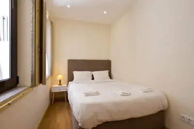 a bedroom with a large white bed with a window at Aposentus - CS Trindade Apartments in Porto