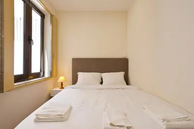 a white bed in a white room with a window at Aposentus - CS Trindade Apartments in Porto