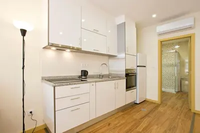 a white kitchen with a sink and a refrigerator at Aposentus - CS Trindade Apartments in Porto