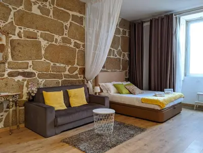 a bedroom with a couch and a stone wall at Porto-Stone Wall Apartment in Porto