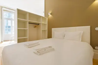 a bedroom with a white bed with towels on it at APOSENTUS - Your home in Almada in Porto