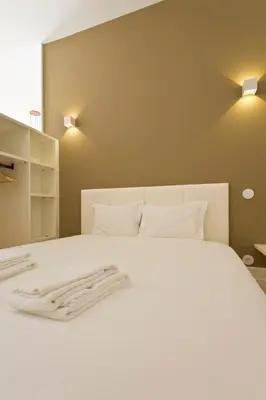 a bedroom with a white bed with two towels on it at APOSENTUS - Your home in Almada in Porto
